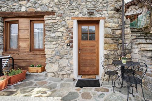 a stone house with a wooden door and a table and chairs at Mini House Valle d'Aosta in Roisan