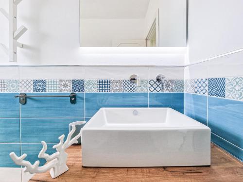 a bathroom with a white tub and blue tiles at Casa Diamante Blu Mare in Marina di Campo