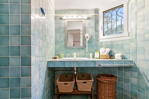 a blue tiled bathroom with a sink and wicker baskets at Villa Les Dauphins in Le Lavandou