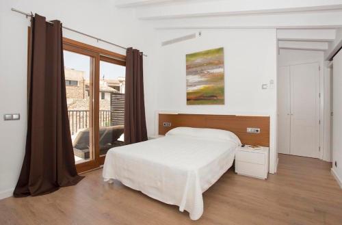 a white bedroom with a bed and a large window at Casa Sant Sebastia in Pollença