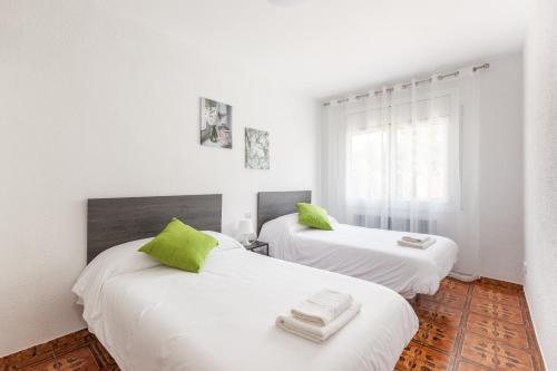 two beds in a room with white walls and green pillows at Apartamento Villa Mercedes in Rubí