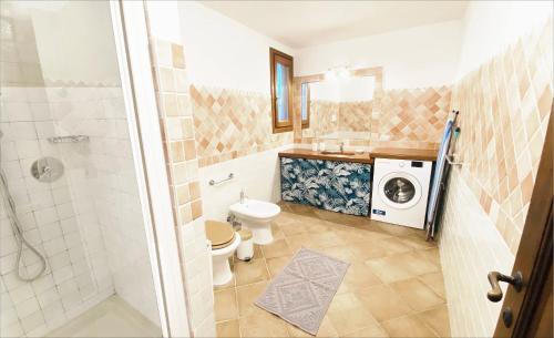 a bathroom with a toilet and a washing machine at Villa Ida Isuledda in San Teodoro