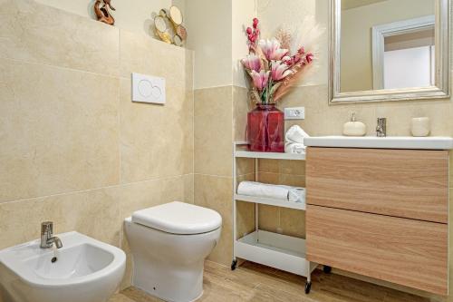 a bathroom with a toilet and a sink and a vase of flowers at Dependance con piscina in Punta Molara