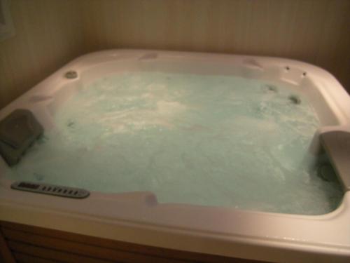 a bath tub filled with blue water in a bathroom at Gite bord de mer jacuzzi in Plougrescant