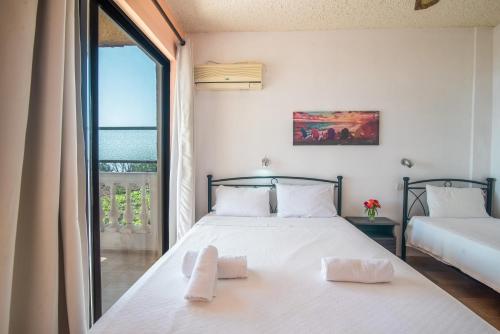 a bedroom with two beds and a large window at Andromaches apartment sea view in Corfu