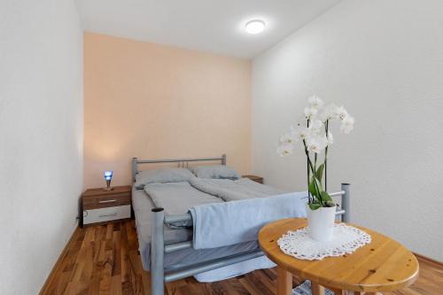 a bedroom with a bed and a table with flowers on it at Nichtraucher-Ferienwohnung Sandhaas in Ringsheim