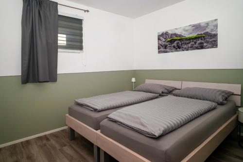 two beds in a room with green walls and a window at Apartment 5 in Rielasingen-Worblingen