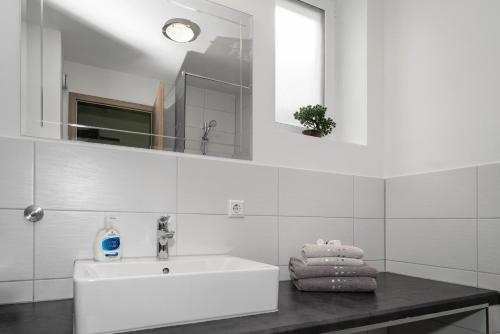 a white bathroom with a sink and a mirror at Apartment 5 in Rielasingen-Worblingen