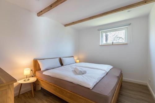 ein Schlafzimmer mit einem Bett mit weißer Bettwäsche und einem Fenster in der Unterkunft Holtdeel in Gelting