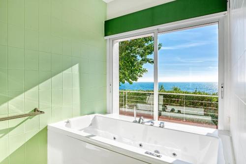 a white tub in a green bathroom with a window at Perla del Mar Calpe in Benissa