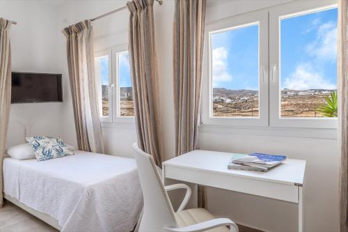 a bedroom with a bed and a desk and window at Afroditi Ftelia Anemone in Mykonos