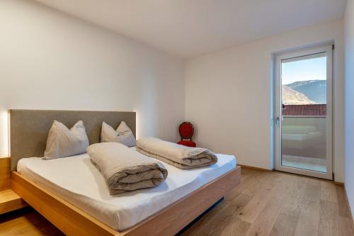 a bedroom with a bed with a large window at Ferienwohnungen Karin - Lagrein in Termeno