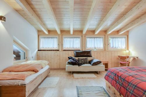 a bedroom with two beds and a chair and windows at Ciasa Christina - Attic in Moena
