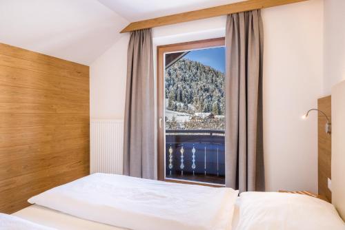a bedroom with a bed and a large window at Rosalpina Apt 3 in San Vigilio Di Marebbe