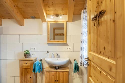 a bathroom with a sink and a wooden door at Apartment Ferienhaus Huber in Grainau