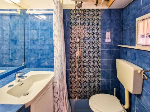 a blue tiled bathroom with a toilet and a sink at Il Borgo 5 in Capoliveri