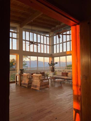 a large room with chairs and a table and windows at Stunning villa w pool & mountain view in Jarabacoa in Jarabacoa