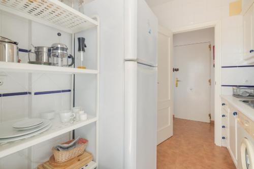 a kitchen with white cabinets and white appliances at Atico En Islantilla in Huelva