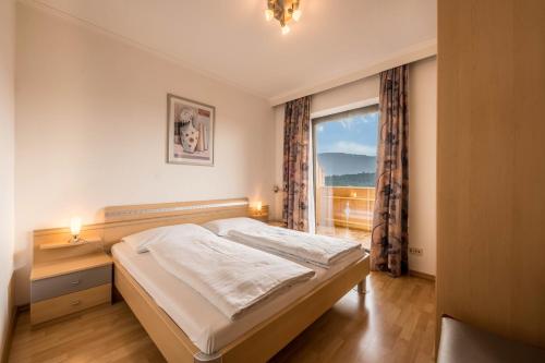 a bedroom with a bed and a large window at Residence Kronstein - Fewo 6 in Tesimo