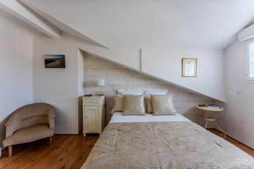 a bedroom with a large bed and a chair at La Chambre Dorée du Bassin in La Teste-de-Buch