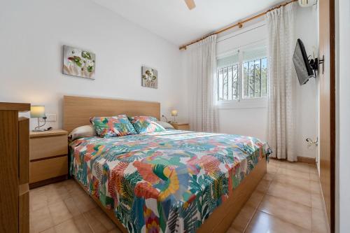 a bedroom with a bed with a colorful bedspread and a window at Traditional Villa in Creixell
