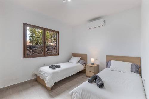 two beds in a room with a window at Casa Tajinaste in Tijarafe