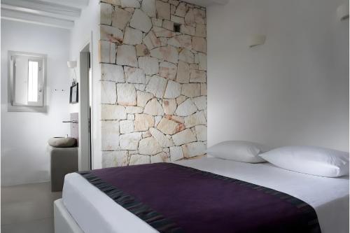 a bedroom with a stone wall and a bed at Echinousa Kimolos katoikia no2 in Kimolos
