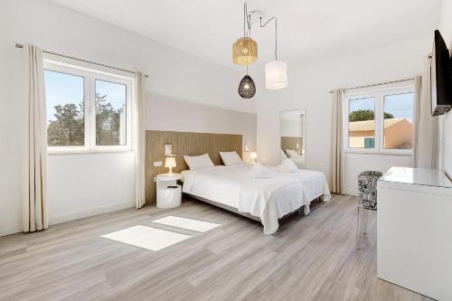 a white bedroom with a bed and two windows at Soltroia Beach Court -Heated Pool in Troia