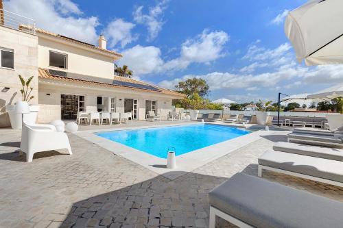 a villa with a swimming pool in front of a house at Soltroia Beach Court -Heated Pool in Troia