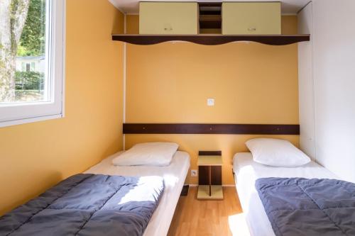 two beds in a room with yellow walls at Mobilhome Le Chene in Saint-Pompont
