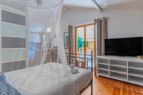 a bedroom with a bed and a flat screen tv at La maisonnette en bois in Saumos