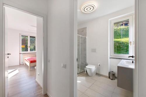 a white bathroom with a toilet and a sink at Ghome and Home Lake view Apartment in Civenna