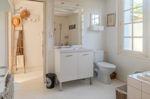 a white bathroom with a toilet and a sink at Villa au bord de la Charente in Jarnac