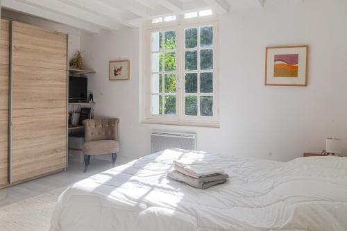 a white bedroom with a bed and a chair at Villa au bord de la Charente in Jarnac