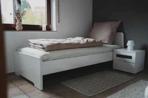 a white bed with a night stand and a window at Ferienwohnungen Bullau - 2 in Erbach