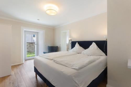a bedroom with a large bed with white sheets and pillows at Torhaus Schloss Wocklum in Balve