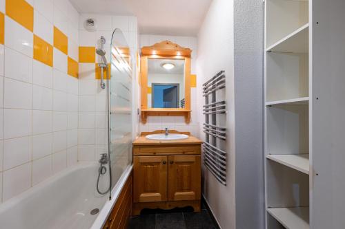 a bathroom with a sink and a tub and a mirror at Appartement C21 in Valloire