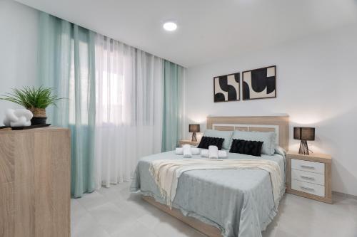 a white bedroom with a large bed and curtains at Apartamento Iris Tropical in Araya