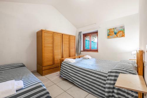 a bedroom with two beds and a wooden cabinet at La Capannuccia C in Ansedónia