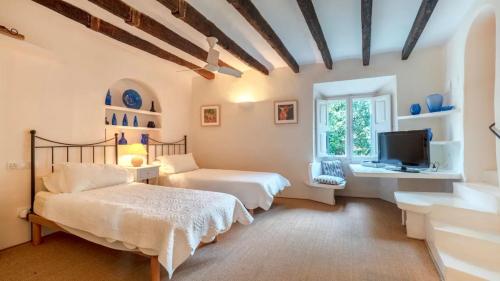 two beds in a room with a tv and a window at Sol y Montes in Fornalutx