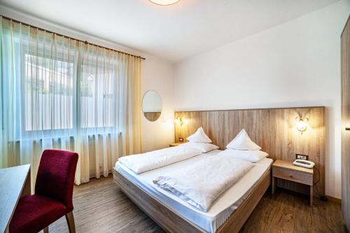 a bedroom with a large bed and a red chair at Gartenheim App Franz in Schenna