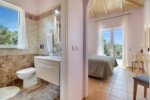a bathroom with a toilet and a sink and a bed at Villa Belvedere Rosa in Lefkada