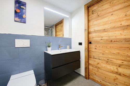 a bathroom with a sink and a toilet and a wooden door at La Pièce de Leo in Châtillon