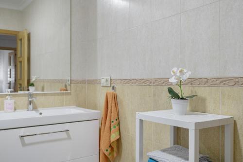 a bathroom with a sink and a vase of flowers on a table at Casa Unifamiliar Rio Barbate in Barbate