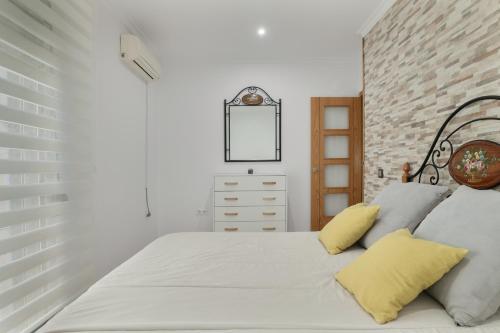 a bedroom with a white bed with yellow pillows at Casa Unifamiliar Rio Barbate in Barbate