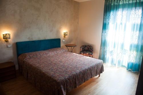 a bedroom with a bed and a window with blue curtains at Casa di Olly in Sona