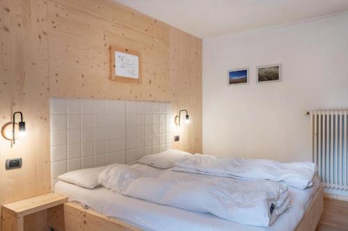 a bedroom with a large bed with white sheets at Apartment Sassolungo in Campitello di Fassa