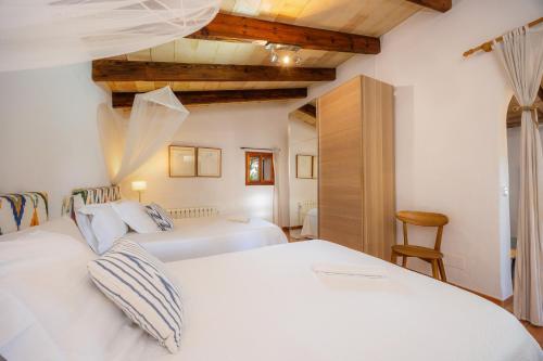 a bedroom with two white beds and a wooden ceiling at Finca Rural Es Pujol in Sóller