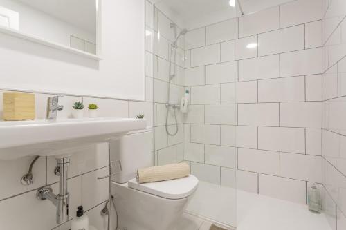 a white bathroom with a toilet and a sink at Oasis Duna - Casa Amanay in Corralejo
