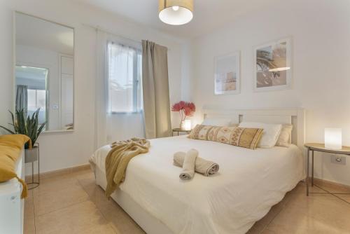 a bedroom with a large white bed with towels on it at Oasis Duna - Casa Amanay in Corralejo